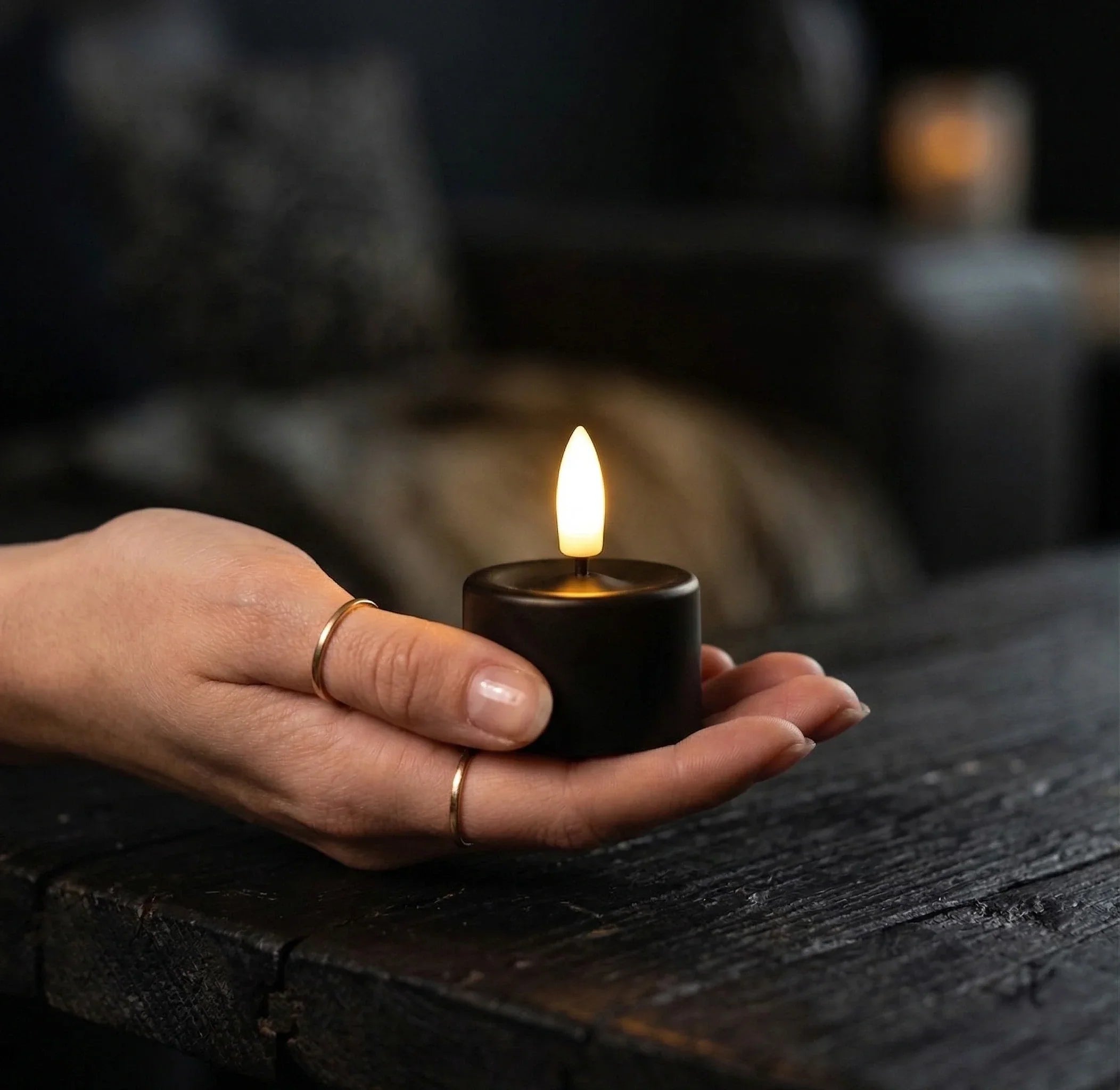 Vrouw met zwart oplaadbaar waxinelichtje: Vergelijking tussen oplaadbare waxinelichtjes en batterij waxinelichtjes met verschillen in brandduur en gebruik