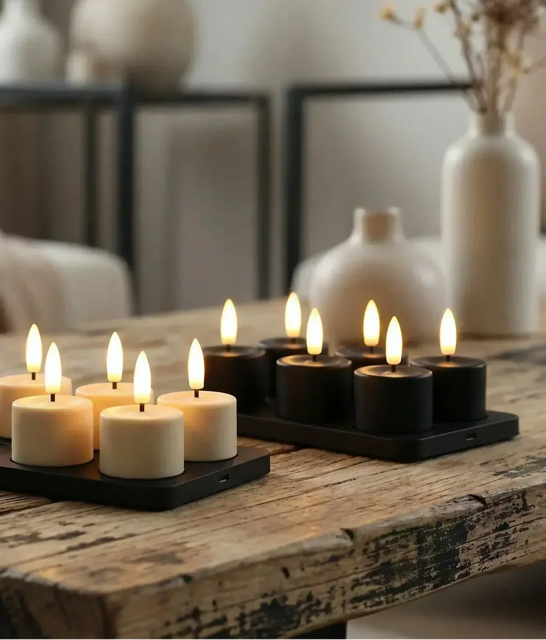 Oplaadbare waxinelichtjes met laadstation van de GlowPro serie in zwart en ivoor op een houten tafel.