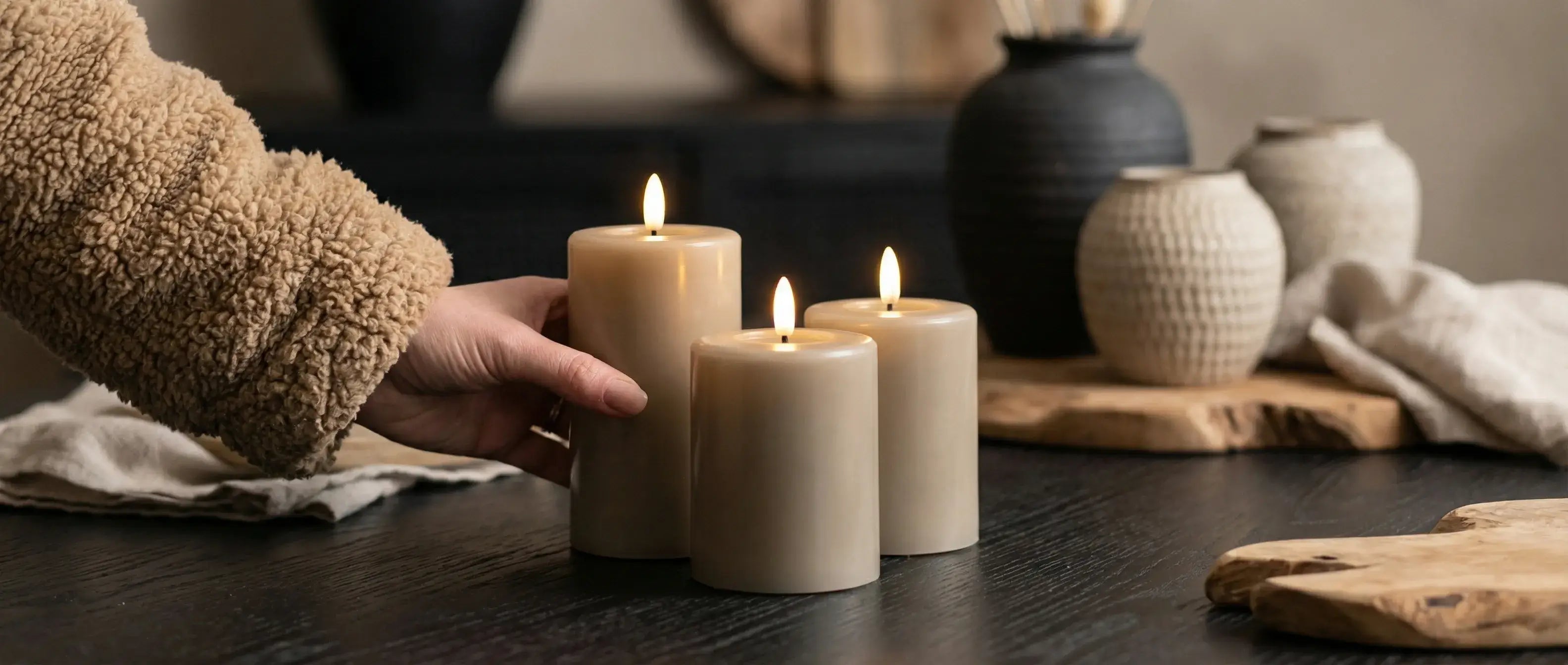 GlowPro set van 3 oplaadbare stompkaarsen in taupe kleur van KENN® op een zwarte tafel.