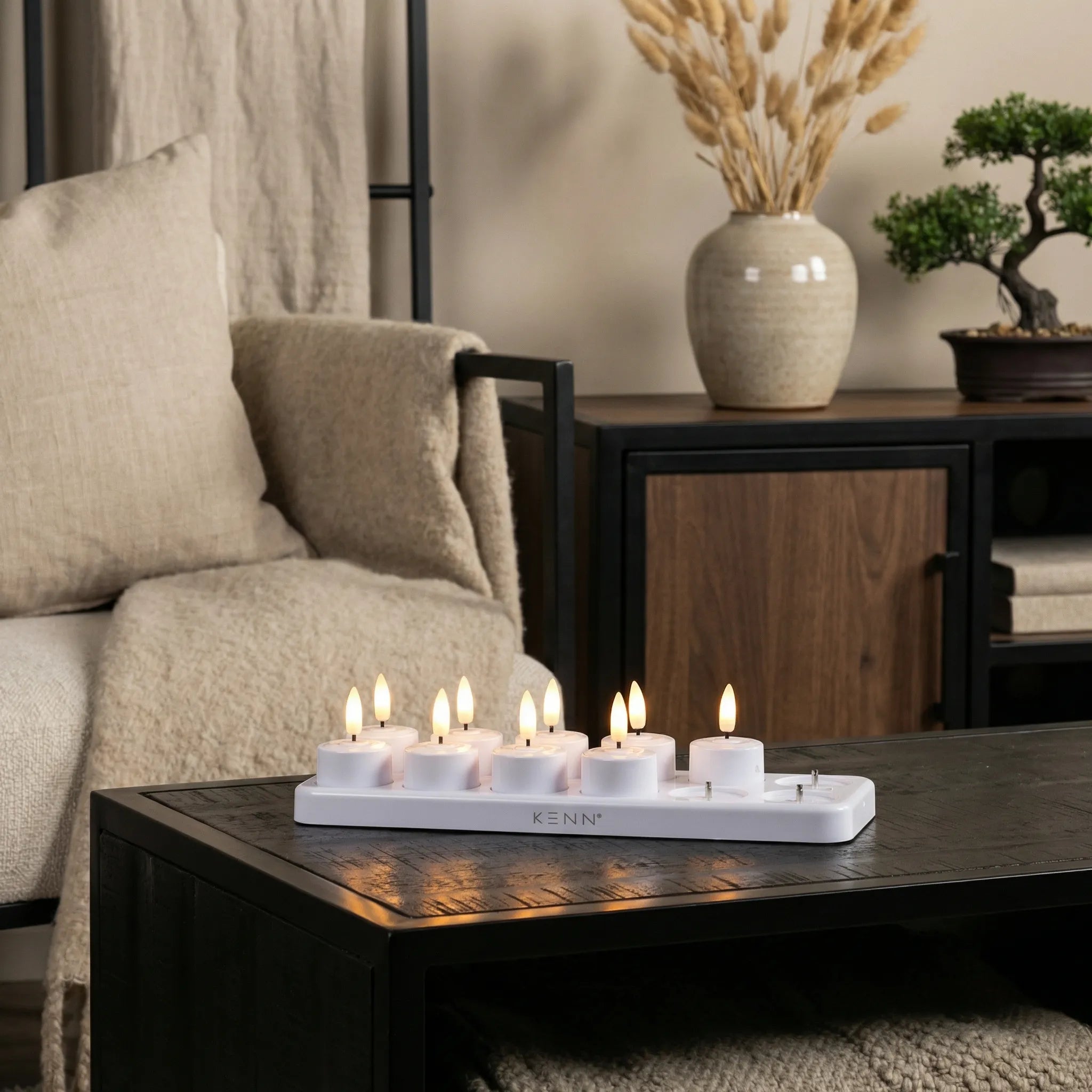 KENN set van 12 oplaadbare waxinelichtjes met laadstation op een houten tafel in een gezellige woonkamer.